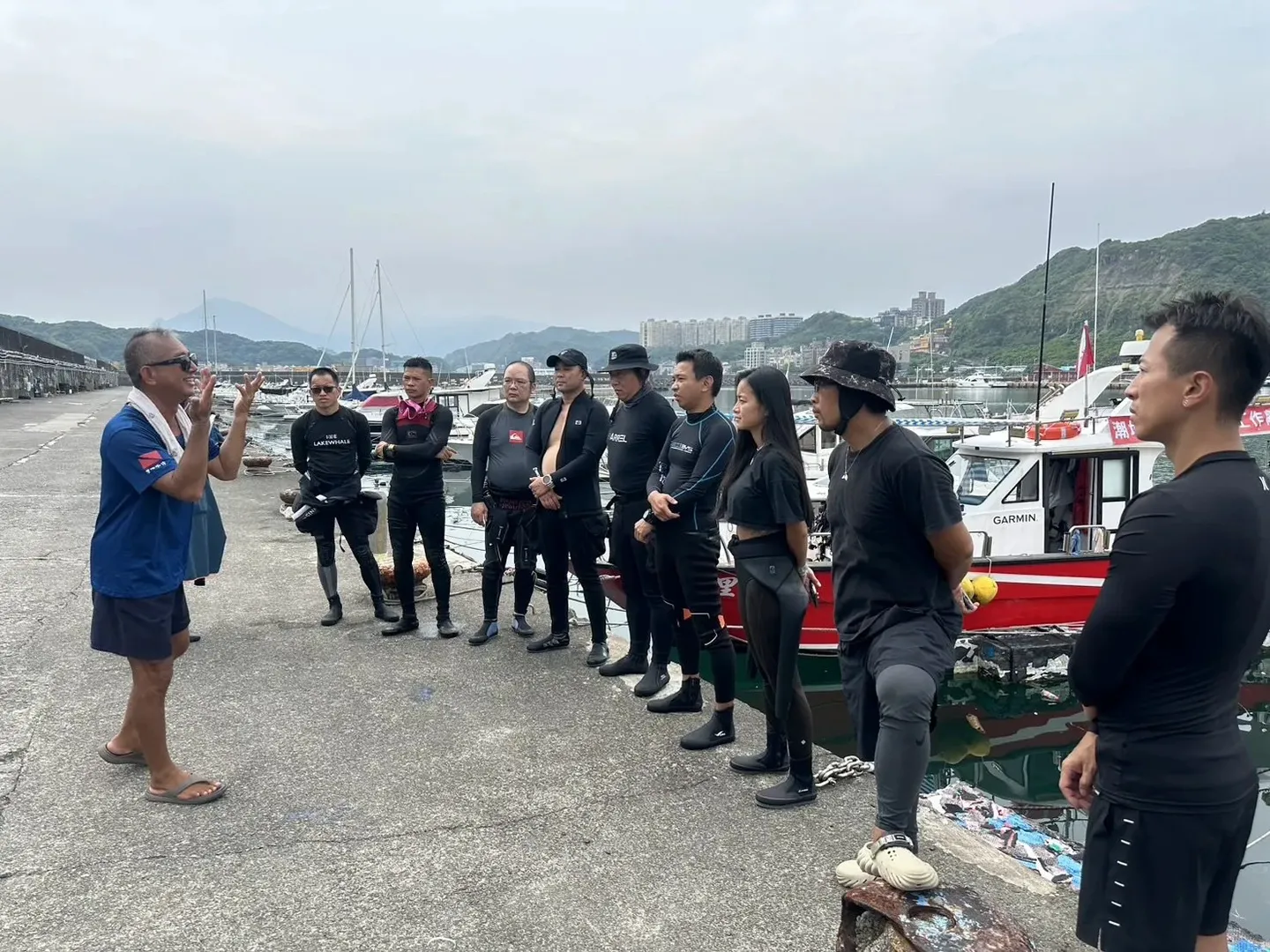 岸邊行前簡報,帶隊者向一排著裝完畢的潛水員說明淨海任務與注意事項
