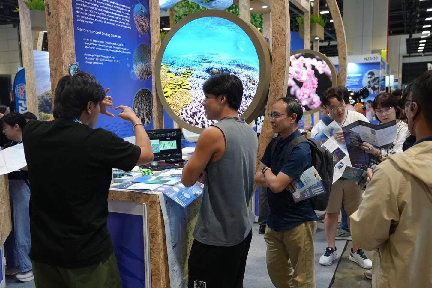 新加坡訪客在 ADEX 2026 台灣館攤位拿介紹手冊