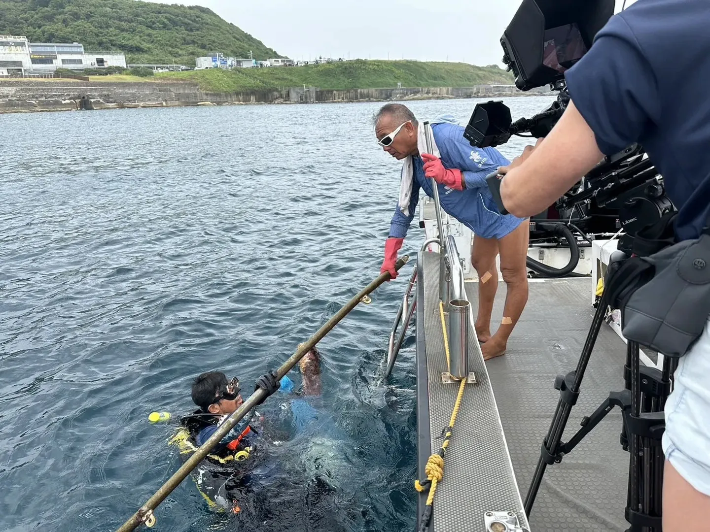 潛水員在船邊把裝滿海廢的收集袋交給船上的工作人員
