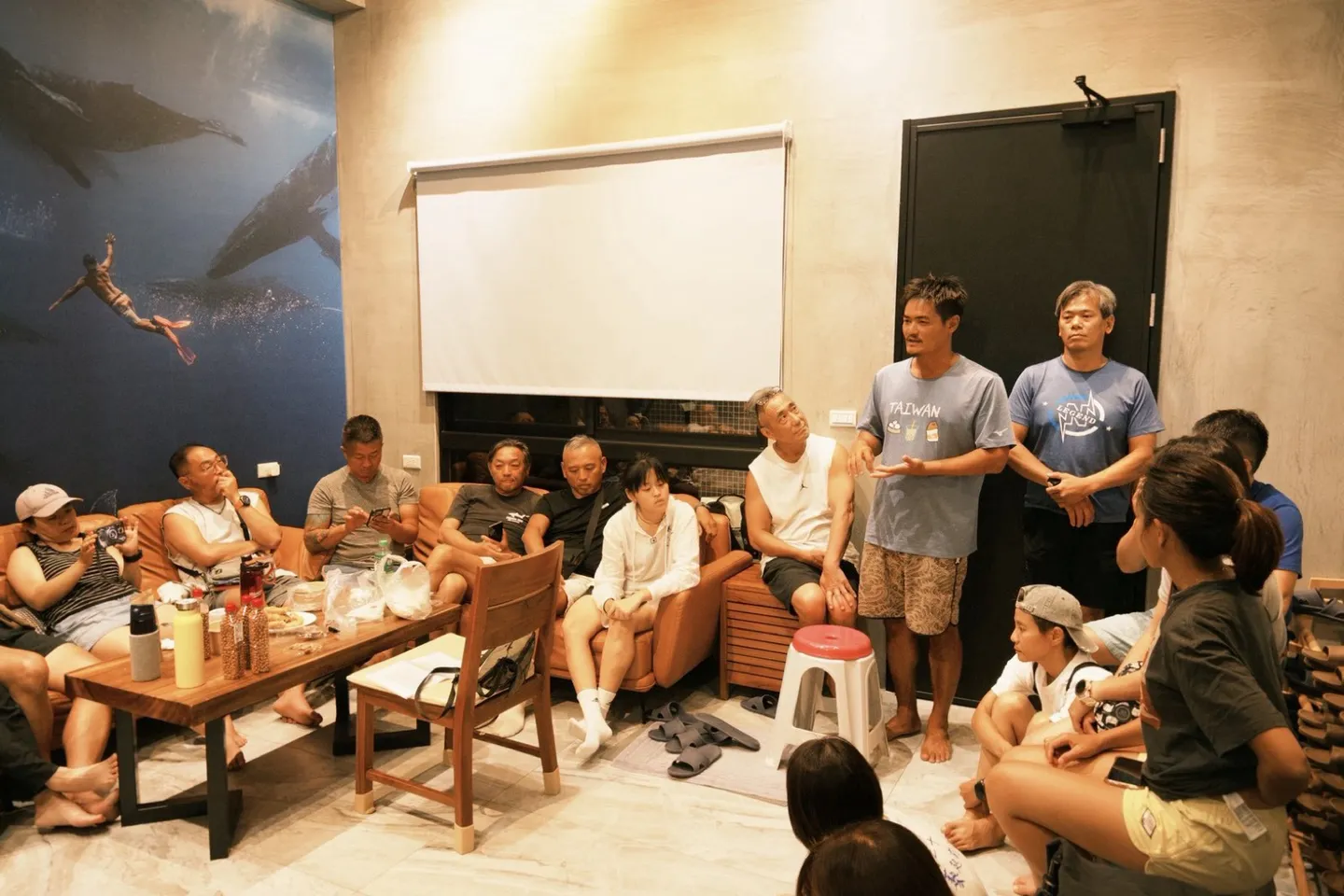 岸邊行前簡報，帶隊者站著向圍坐一圈的潛水員說明淨海任務分組與水下作業方式