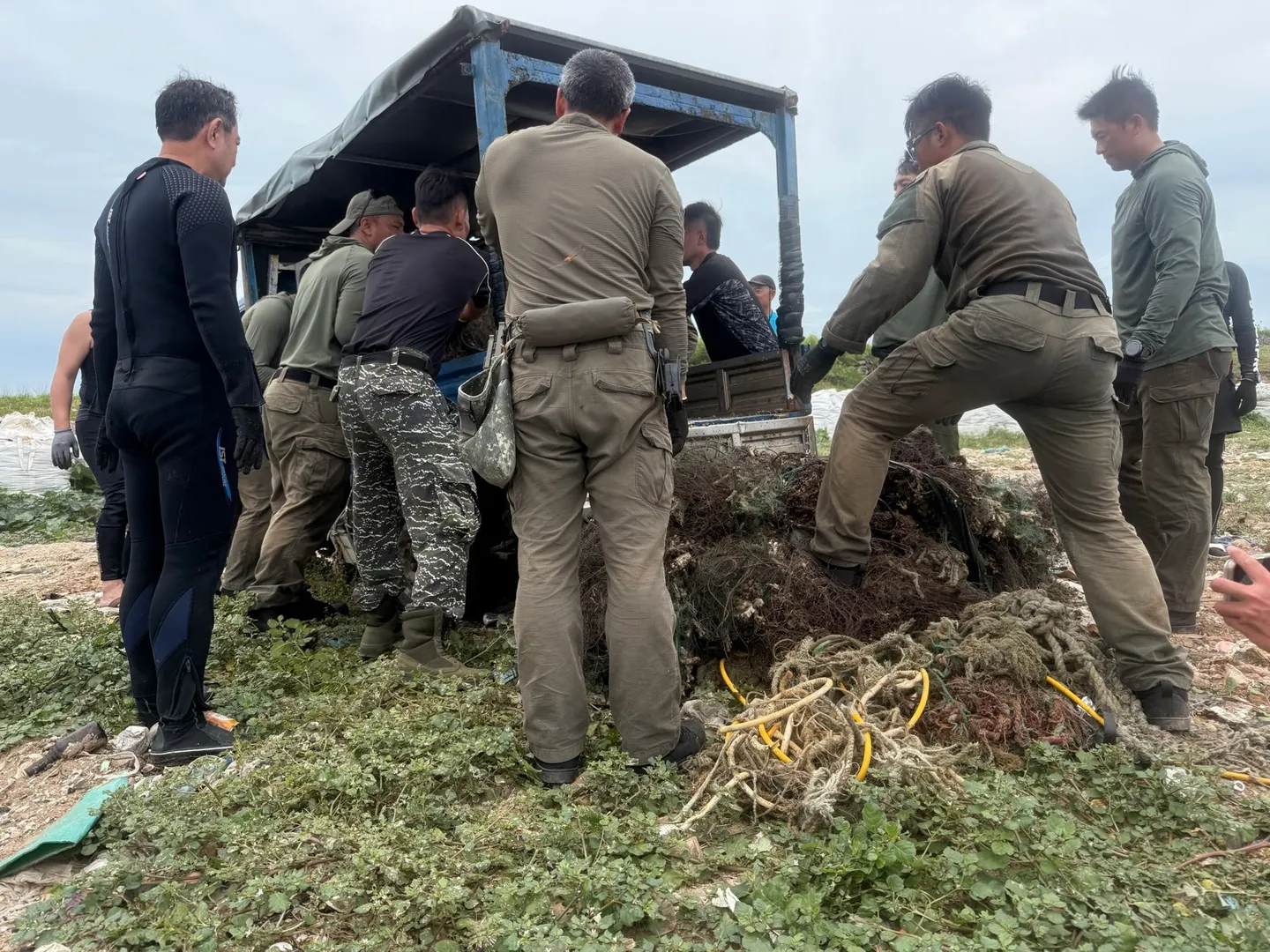 國軍弟兄與潛水員合力將一大團纏滿岩石與死珊瑚的廢棄漁網抬上藍色板車
