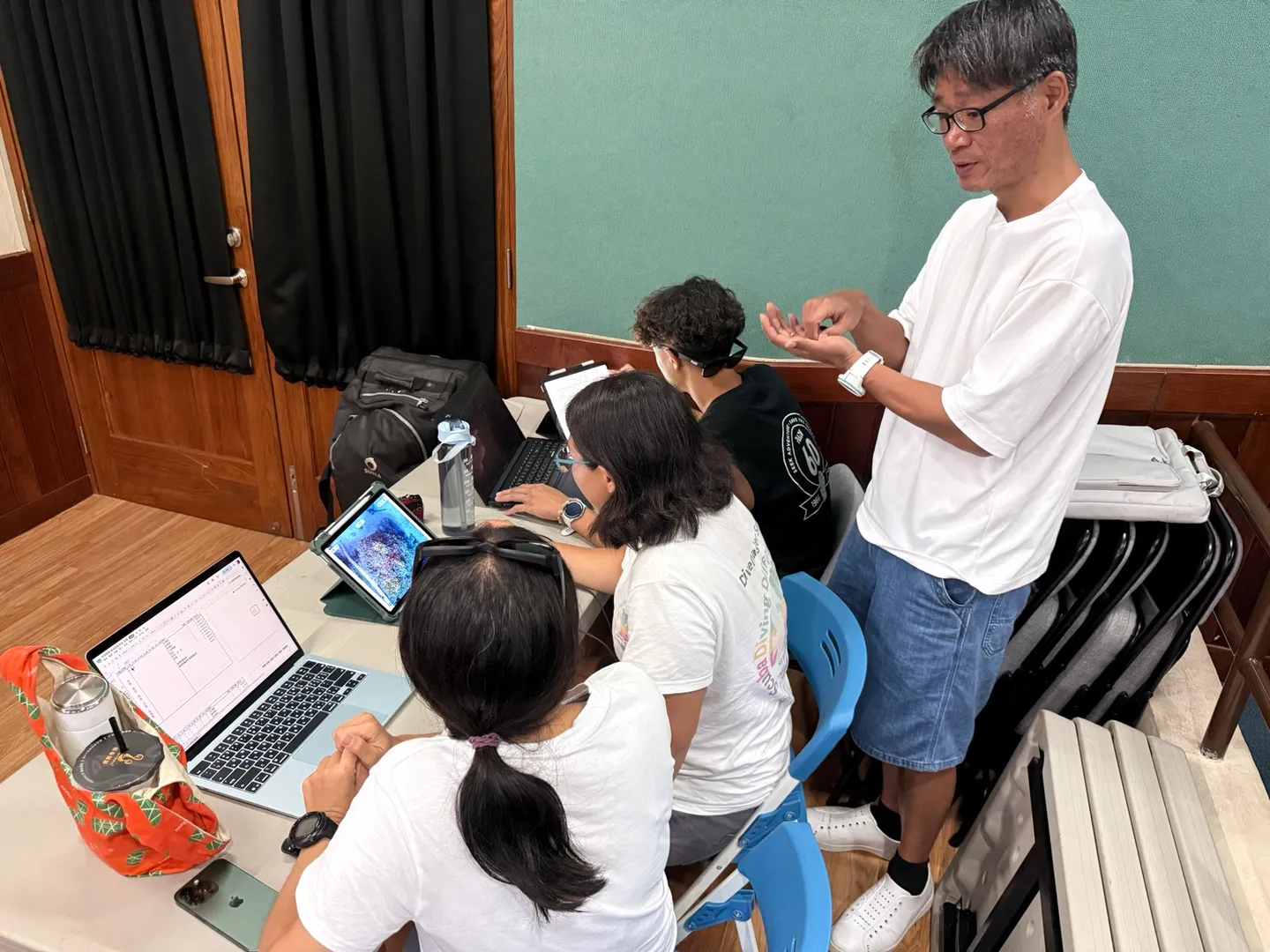 高雄科技大學沒骨氣實驗室老師與公民科學家一起檢視筆電上的珊瑚監測數據並討論回報